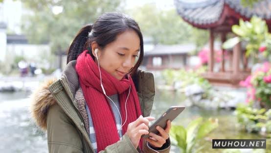 湖边的女人听耳机，用手机上网实拍4K视频Woman listen to earphone and surf the internet on mobile phone in china插图
