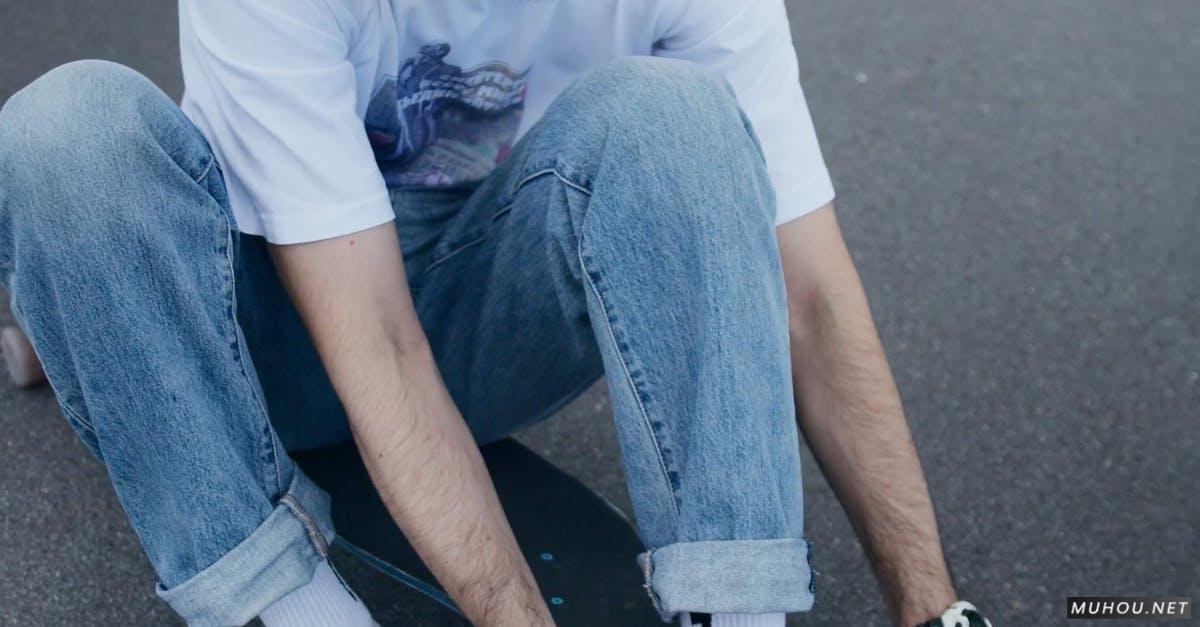 夏天牛仔裤男人在滑板上系鞋带4k高清CC0视频素材