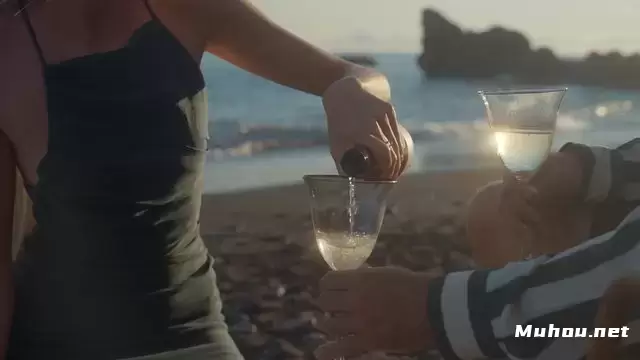 日落时分一名妇女在海滩上将香槟倒入玻璃杯中视频素材