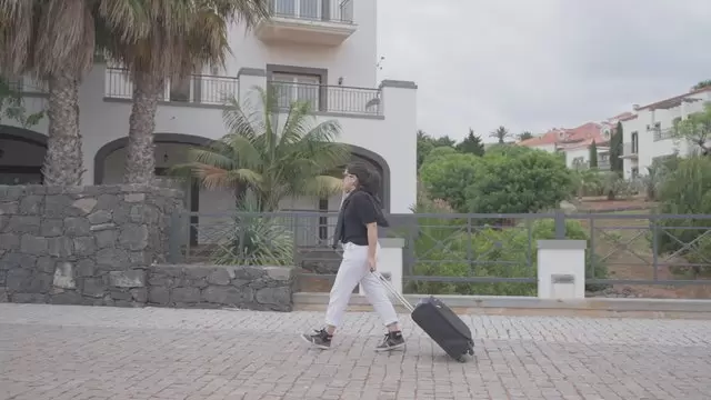 一个女人带着手提箱走到酒店视频素材