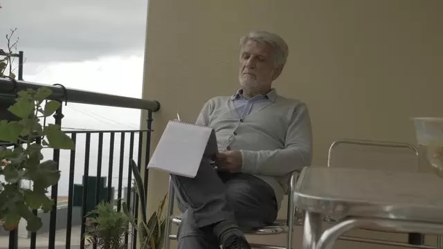 一个老人坐在外面，一边在笔记本上画画视频素材