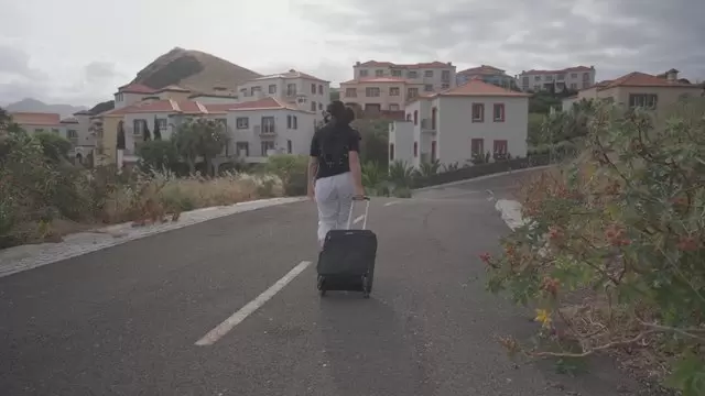女人带着手提箱走在马路上视频素材